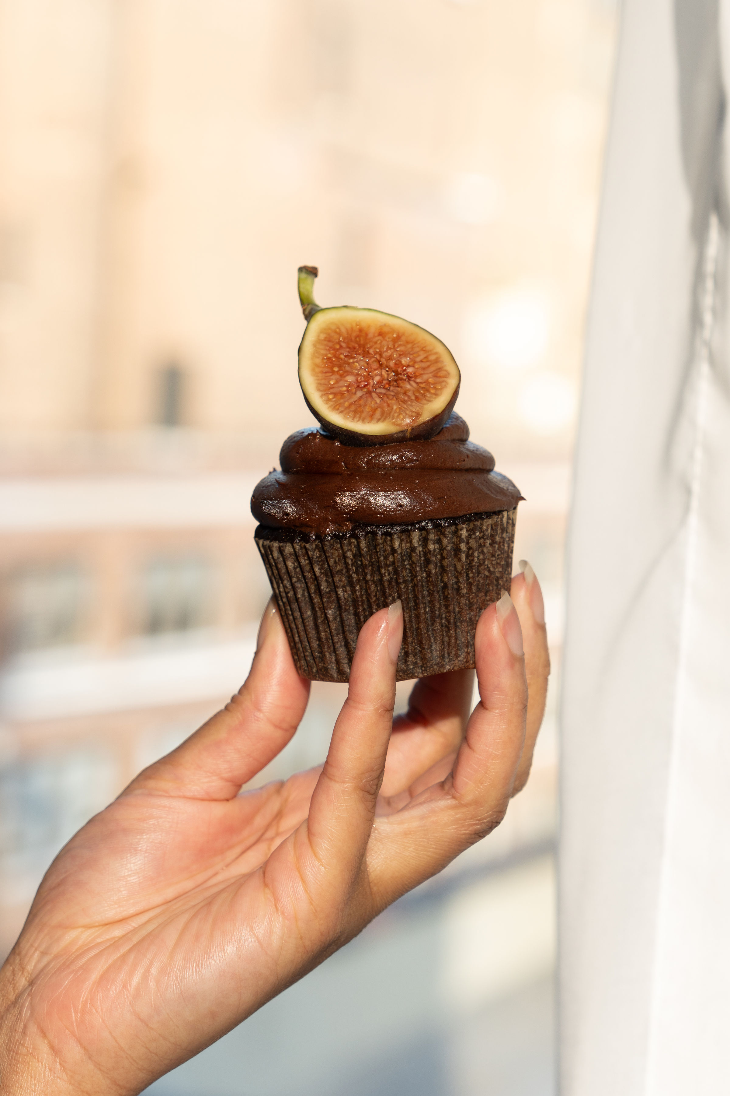 A chocolate cupcake topped with a fresh fig